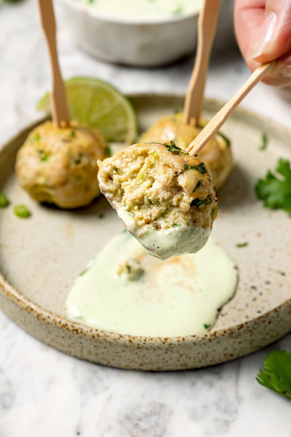 These Southwest baked turkey meatballs are made with jalapeño, cilantro and cumin for a light, tasty twist on classic meatballs! Add them to meal bowls and salads or serve them as an appetizer. Dipping baked turkey meatball into creamy sauce.